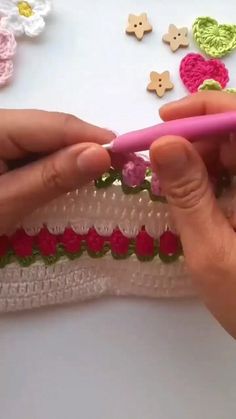 someone is crocheting flowers on the side of a piece of fabric with pink scissors