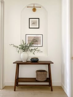 a table with some plants on top of it in front of a white wall and doorway