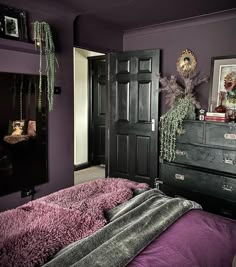 a bedroom with purple walls and an old dresser in the corner is decorated with greenery