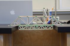 an apple laptop computer sitting on top of a wooden desk next to a model bridge