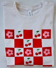 This vibrant cropped tee is the perfect style for spring, displaying a checkerboard of cherries and cherry blossoms. It's comfy with a boxy fit, oversized sleeves and an on-trend drop shoulder. It's also super soft! It comes in an off-white color with multicolored graphic, in women's sizes. Cherry Graphic, Style For Spring, Oversized Sleeves, Oversize Sleeves, Cropped Tee, Perfect Style, Off White Color, Cherry Blossoms, Crop Tee