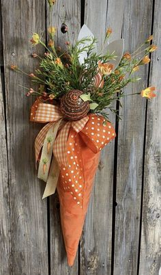 an orange flower arrangement hanging on the side of a wooden fence with polka dot ribbon