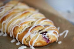 a pastry with white icing on it sitting on a piece of waxed paper