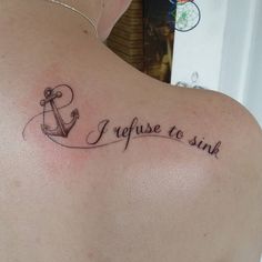 the back of a woman's shoulder with an anchor and words written in cursive ink