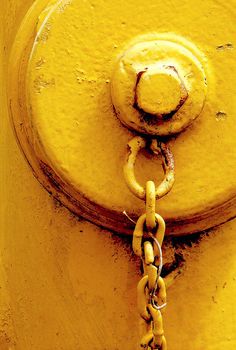 a yellow fire hydrant with chains attached to it