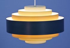 a blue and yellow light hanging from a ceiling fixture with a white stick sticking out of it's center