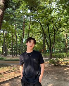 a young man standing in the middle of a park