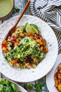 a white plate topped with rice and veggies next to a bowl of sauce