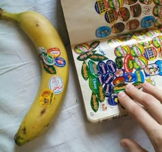 a person's hand reaching for a sticker next to a banana