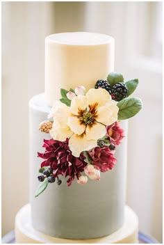 a wedding cake with flowers and berries on top