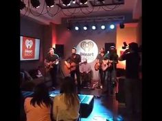 a group of people that are playing guitars in a room with lights on the ceiling