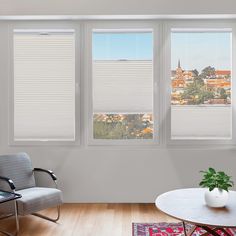 a living room filled with furniture and three windows covered in shades of white cellular shades