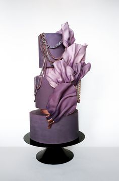 a three tiered purple cake decorated with jewelry