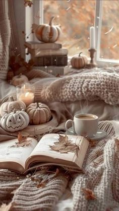 an open book sitting on top of a bed next to a cup of coffee and candles