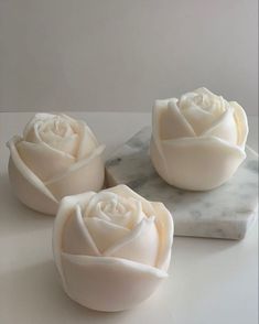 three soap flowers sitting on top of a marble countertop next to a marble block