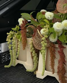 the flowers are growing out of the planters in the back of the car's trunk