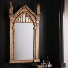 a bathroom with black walls and a gold framed mirror on the wall next to a sink