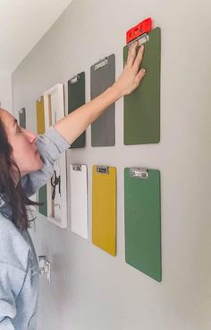 a woman is pointing to some magnets on the wall