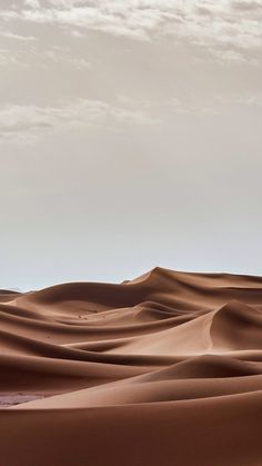 the desert is filled with sand dunes under a cloudy sky