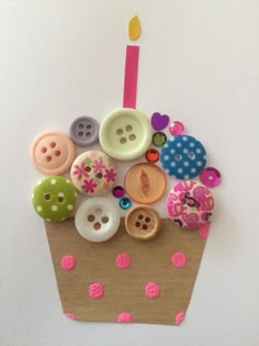 a cupcake decorated with buttons and a candle