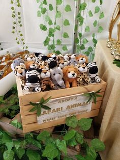 there are many stuffed animals in a wooden box on the table next to green leaves