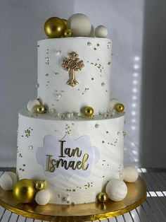 a three tiered cake with gold and white decorations on the top, sitting on a metal rack