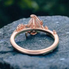 a rose gold ring sitting on top of a rock