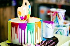 there is a cake decorated with colorful icing and a paint spatula on top