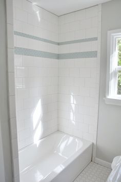 a bathroom with white tile and blue trim