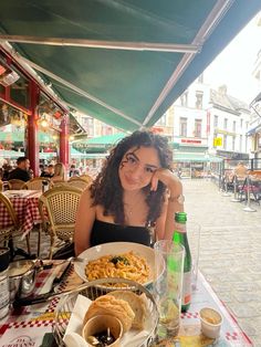 a woman sitting at a table with food on it in front of an outdoor restaurant