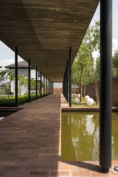 the walkway is lined with black poles and glass windows, along with an artificial pond