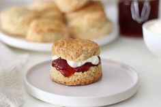 scones with jam and cream on them sitting on a white plate next to other pastries