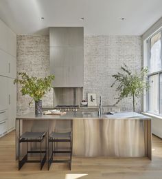 a modern kitchen with stainless steel counter tops and stools in front of the island