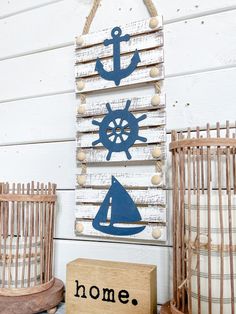 a wooden sign that says home with an anchor and boat on it next to some birdcages