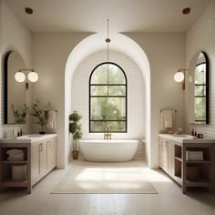 a large white bathtub sitting under a window in a bathroom next to two sinks