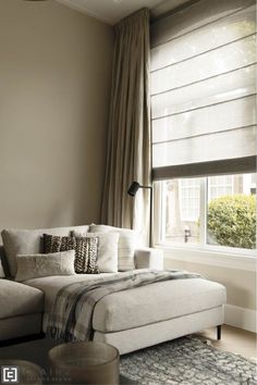 a living room filled with furniture and a large window covered in draping next to a white couch