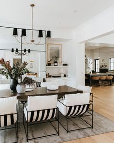 the dining room table is surrounded by black and white chairs with striped cushions on them