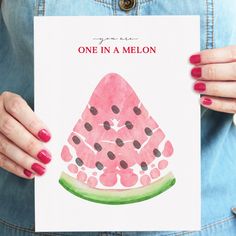 a woman holding up a card with a watermelon on it that says one in a melon