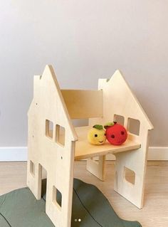 a wooden toy house with fruits and vegetables on the table next to it's steps