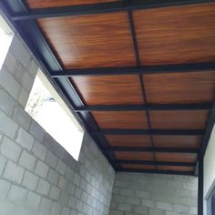 an outdoor covered patio area with brick walls and wood ceilinging, looking into the back yard