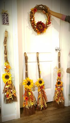 three sunflowers are hanging on the front door and two brooms have been placed next to them