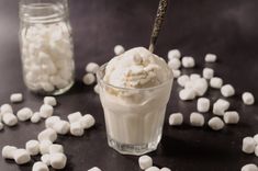 marshmallows are scattered around a small glass cup with ice cream in it