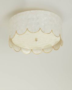 a white ceiling light with scalloped edges and a gold trim around the edge