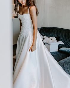 a woman in a white dress standing next to a couch