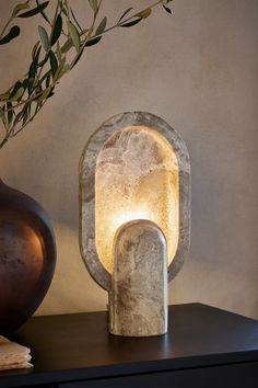 a stone lamp sitting on top of a table next to a vase