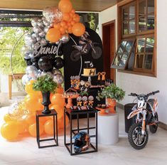 an orange motorcycle is parked in front of a birthday party setup with balloons and decorations