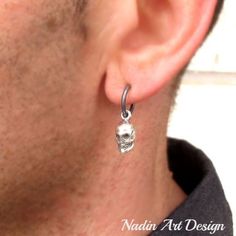 a man wearing a pair of silver earrings with a skull design on the front and side