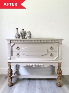 a white dresser with two vases on top of it and the bottom drawer is empty