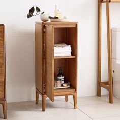 a wooden cabinet sitting next to a toilet in a room with white tile flooring