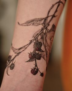 a close up of a person's arm with a tattoo on it and berries